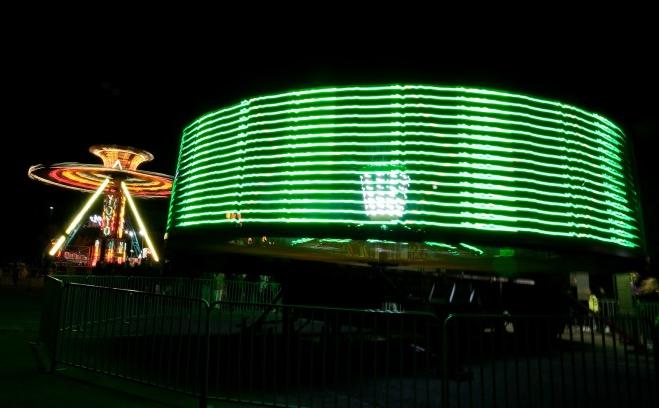 旋转的嘉年华游乐设施上有绿色和金色的灯光