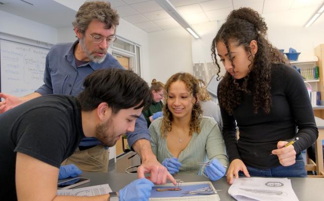 无脊椎动物实验室解剖一只蠕虫，三个学生和教授 